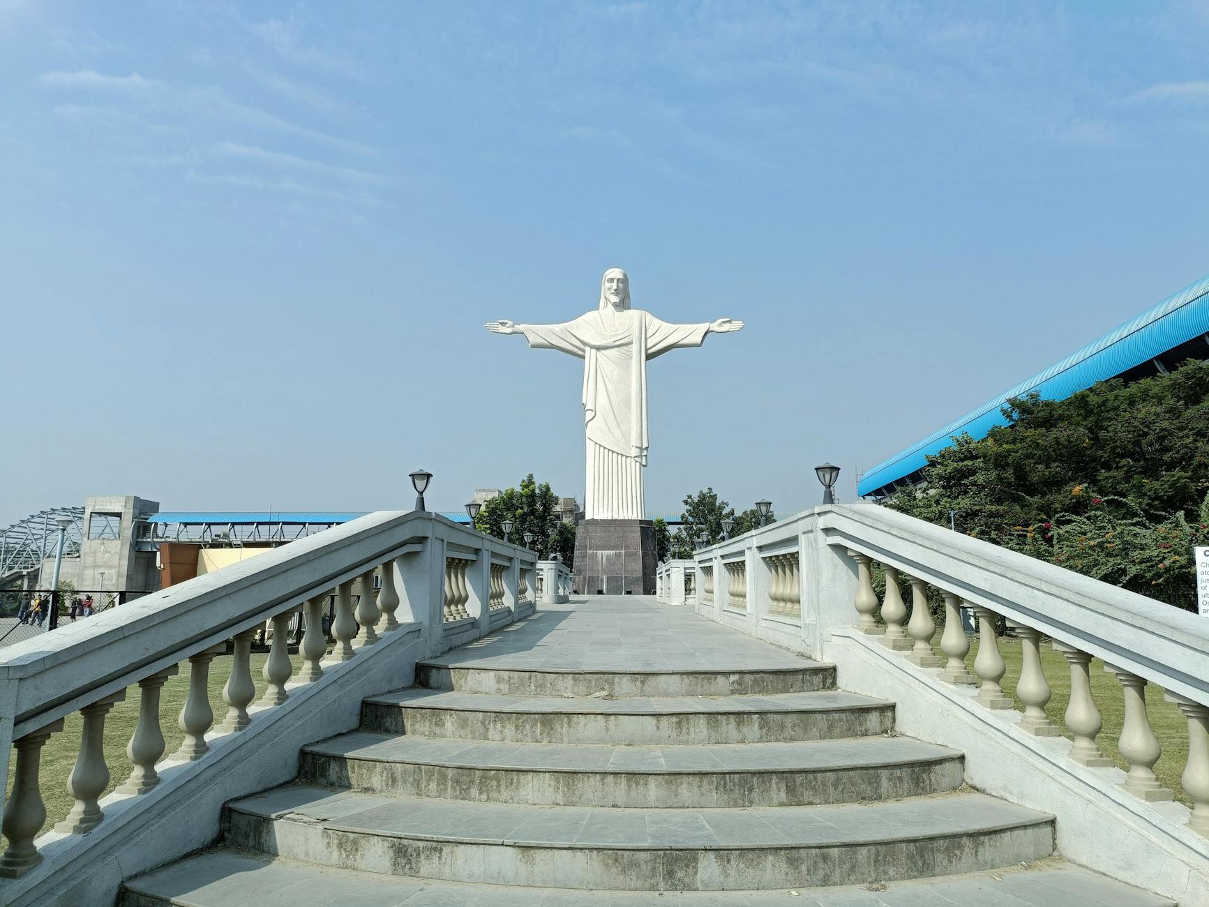 Figura Jezusa Chrystusa Króla z rozpostartymi ramionami na tle błękitnego nieba