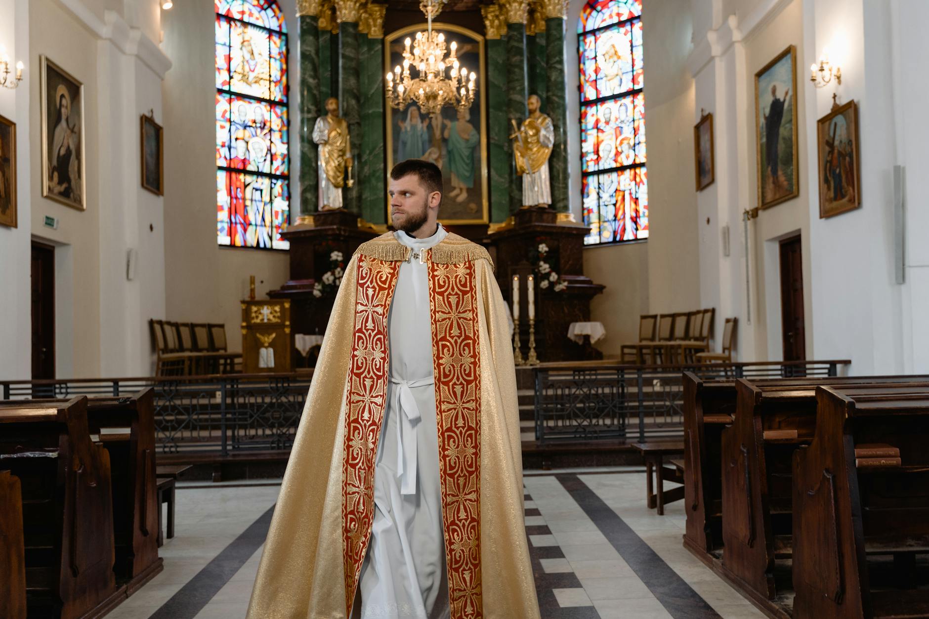 Kapłan w bogatej szacie liturgicznej idzie główną nawą kościoła