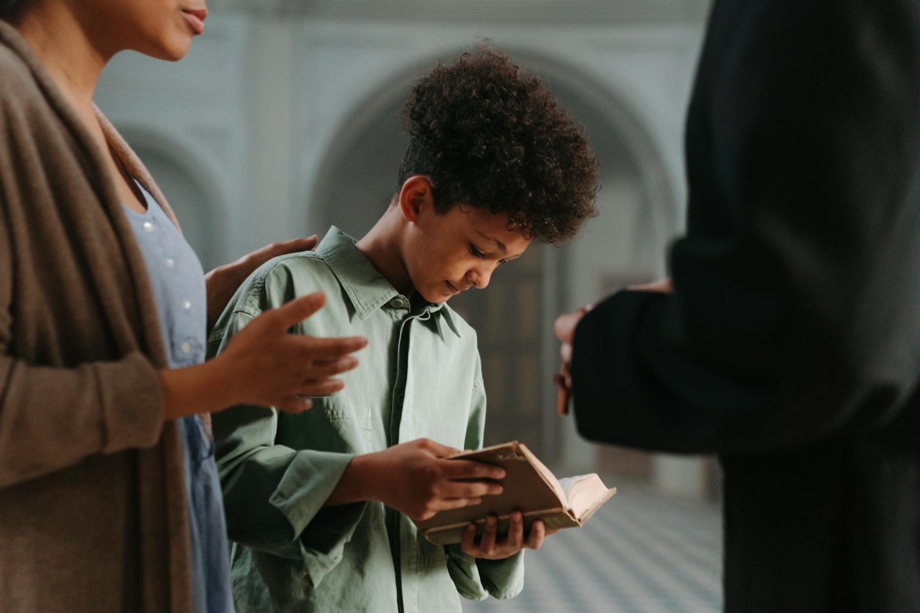 Chłopiec czyta księgę religijną z dorosłymi w kościele