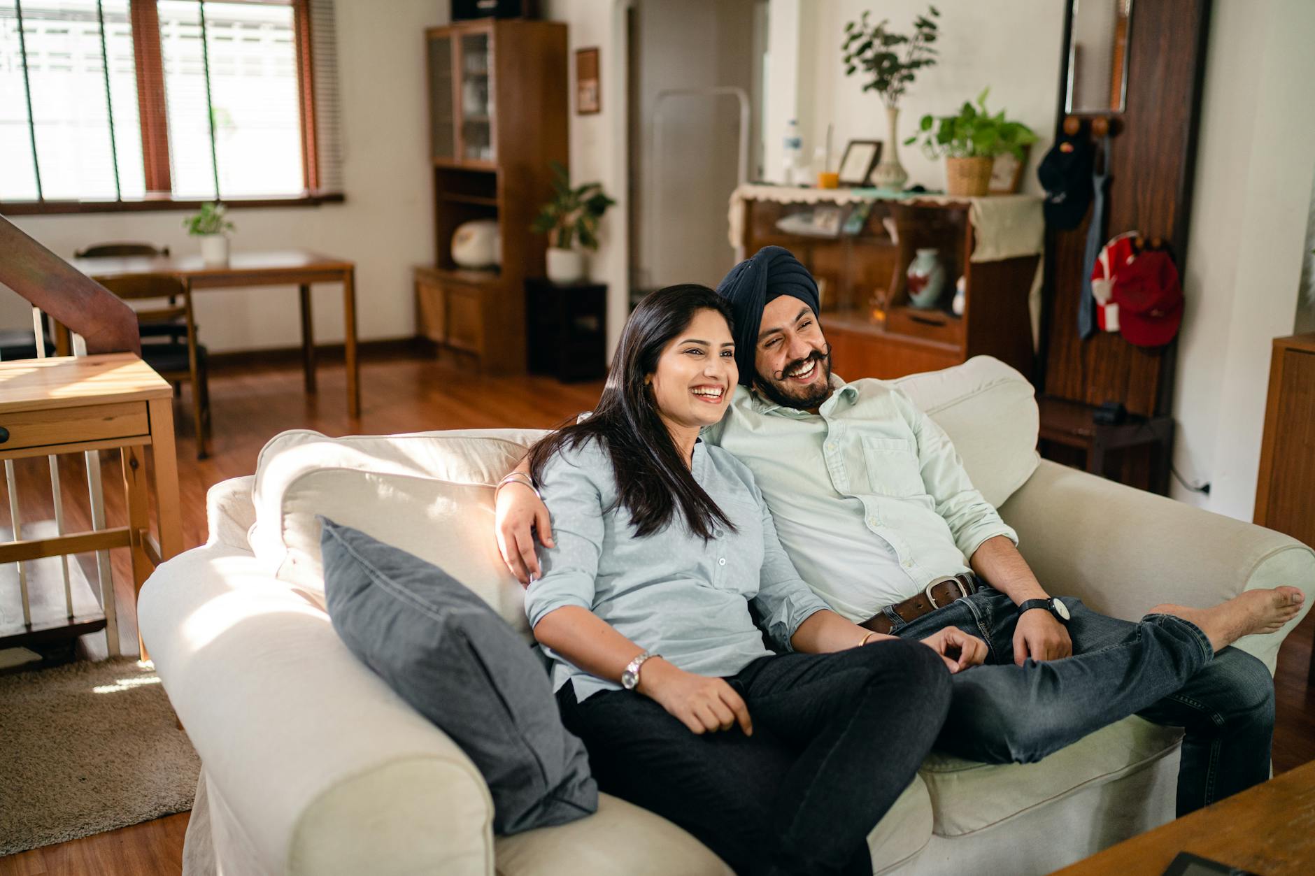 Uśmiechnięte małżeństwo siedzące po turecku i przytulające się w mieszkaniu