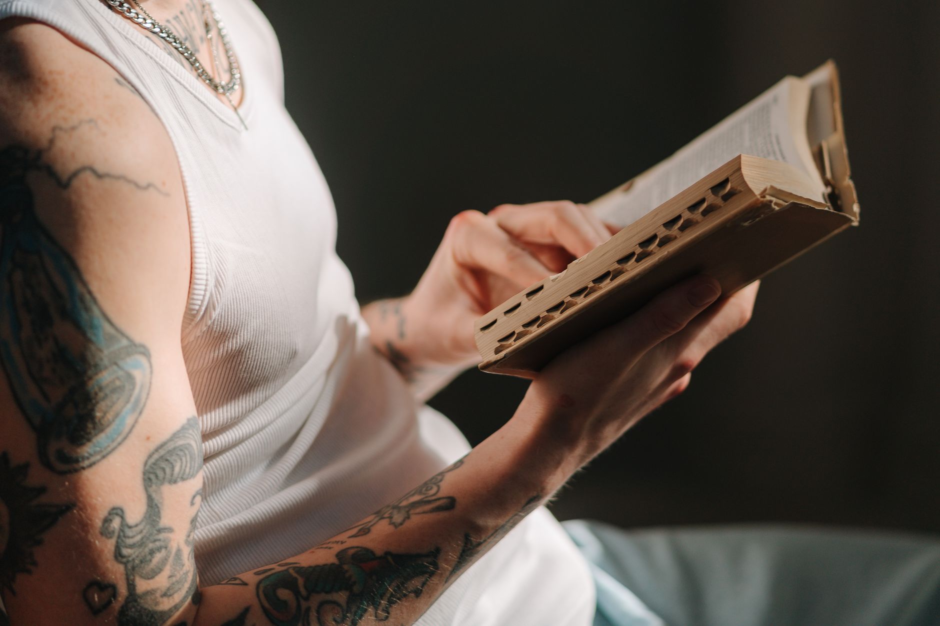Wytatuowana osoba skupiona na lekturze książki z tekstem liturgicznym