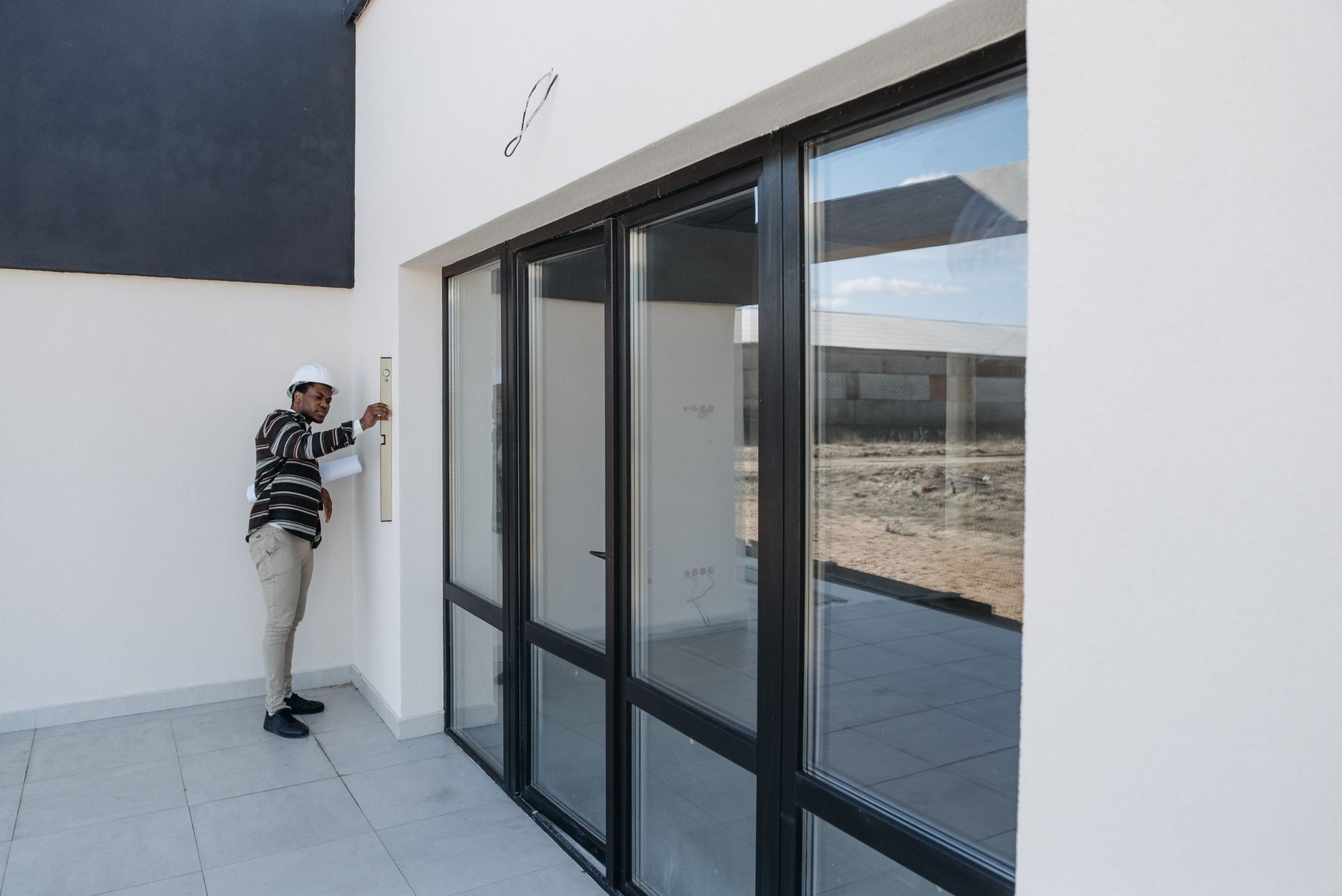 Architekt w kasku kontroluje szklane drzwi w nowoczesnym domu